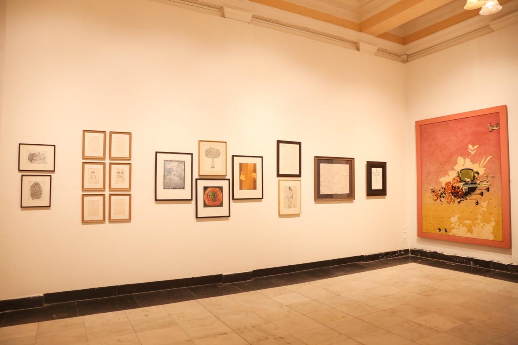 A salon hang of drawings and prints beside the pink Thukral and Tagra carpet.